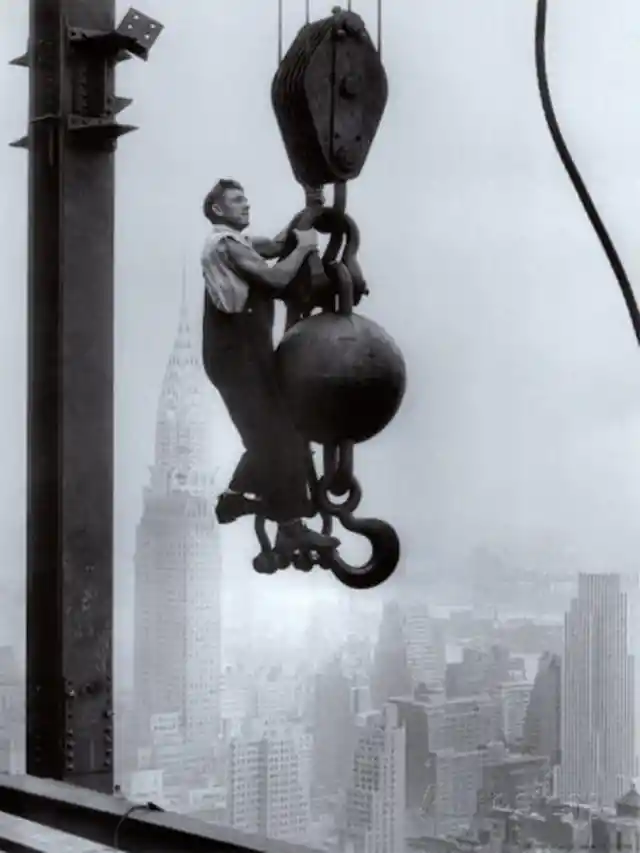 23. An Empire State builder hanging on a crane above New York City, 1925.